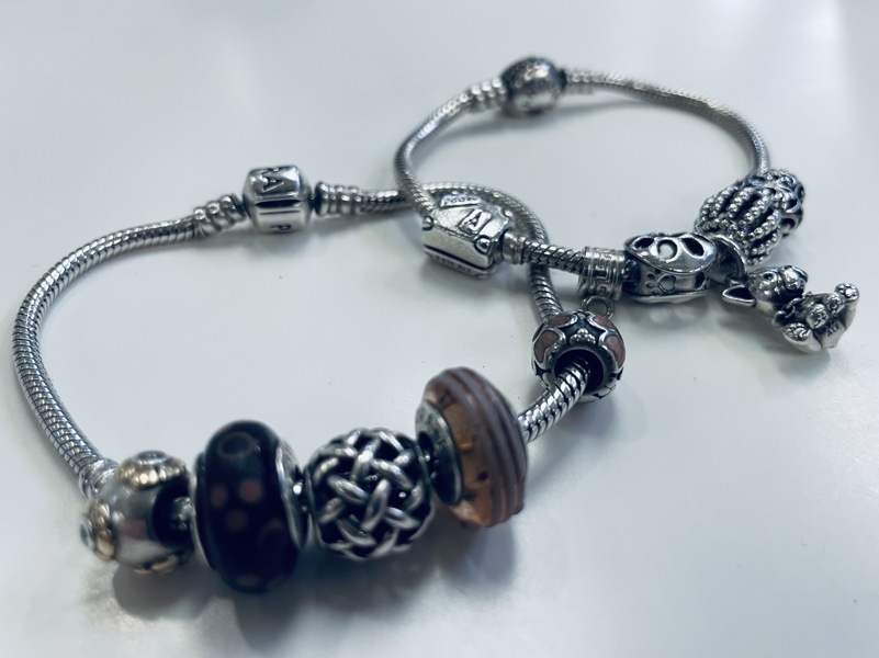 2 Pandora armlænker af sterling sølv (925) prydet med 11 charms (E 2024-0242, 0274)