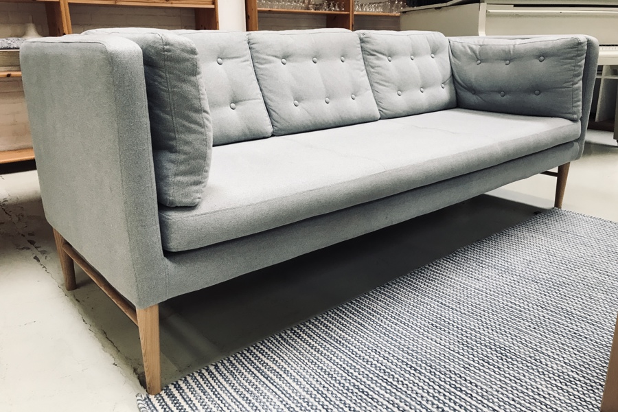 Ilva 3-pers sofa beklædt i lysgråt stof på lyse ben af bøgetræ